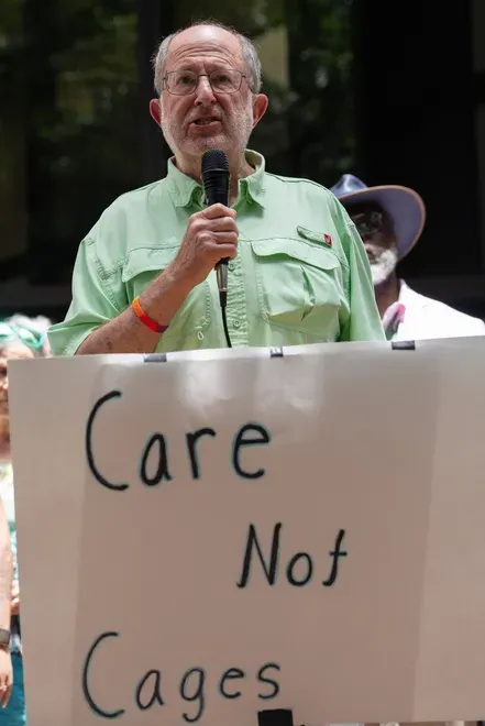 A man is holding a mic talking to a crowd about social justice