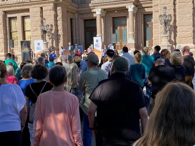 A group of people gathered outside a building to watch a speaker discuss social justice