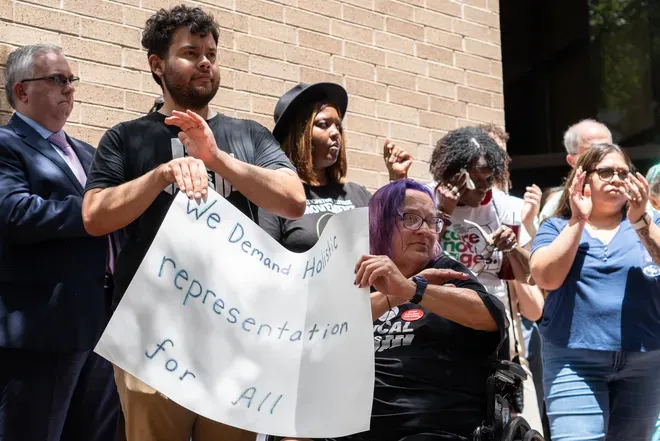 A group of people are outside a building, holding a sign protesting for social justice